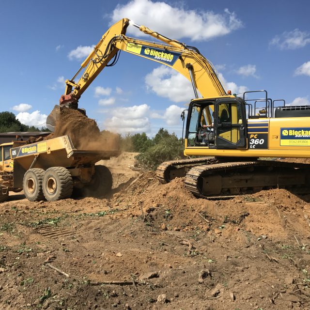 A digger moving soil to a truck
